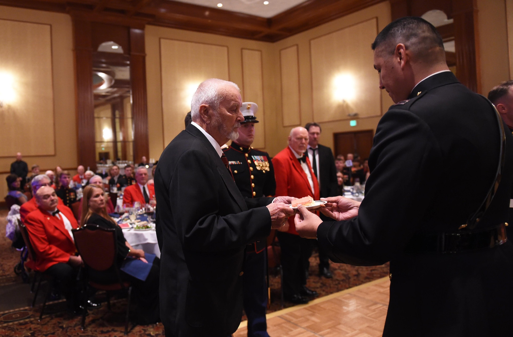 Capt. David Rubio, Company A, Marine Cryptologic Support Battalion commanding officer, passes the first slice of cake to the oldest U.S. Marine during the Marine Corps Birthday Ball Nov. 6, 2015, at the Denver Athletic Club, Denver. The ball was held in honor of the Marine Corps’ 240th birthday, complete with a guest speaker, dinner and dancing. (U.S. Air Force photo by Airman 1st Class Samantha Meadors/Released)