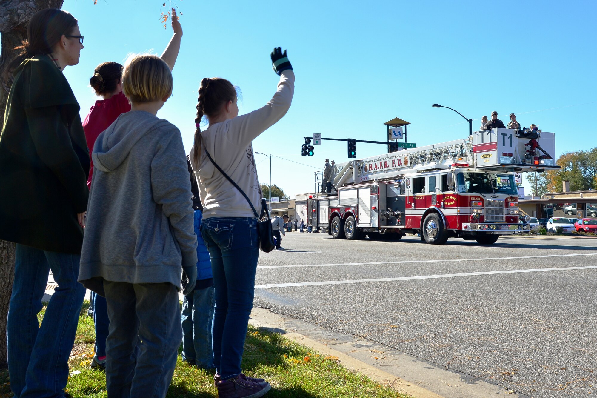 A Hill Air Force Base fire truck passes waving crowds during the annual Veterans Day parade in Ogden, Utah, Nov. 7, 2015. Airmen and equipment from the base participated in the annual event held on Washington St. in downtown Ogden. (U.S. Air Force photo by R. Nial Bradshaw/Released)