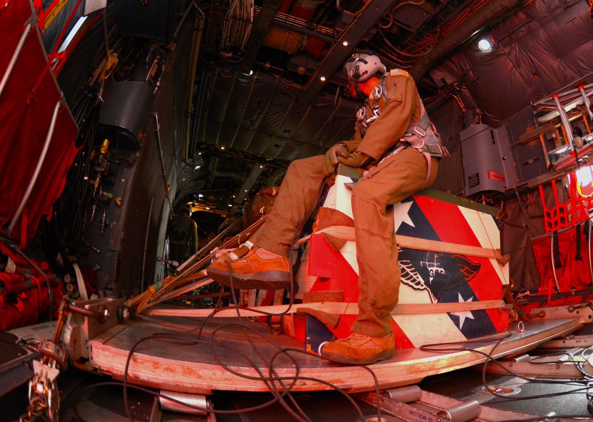 Senior Airman Adrian Robinson, 36th Airlift Squadron loadmaster, sits on top of a heavy equipment pallet while flying over Japan, Nov. 5, 2015. Dropping heavy equipment pallets allows aircrew to practice procedures required to drop real-world heavy equipment, such as vehicles and artillery. The drop was part of the Yokota Air Base’s participation in Exercise VIGILANT ACE 16, a U.S.-Republic of Korea combined exercise aimed at enhancing operational and tactical level coordination through combined and joint combat training (U.S. Air Force photo by Airman 1st Class Baker/Released)