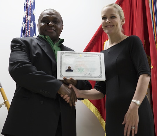 Paul Halstead, left, receives his certificate of naturalization from Kim Shipley, right, special assistant at International Operations of United States Citizens and Immigration Services at the Building One Auditorium at Marine Corps Air Station Iwakuni, Japan, Nov. 5, 2015. In order to become a U.S. citizen, recipients must speak and know English, have good moral character, have knowledge of the U.S. government and history and take the Oath of Allegiance.