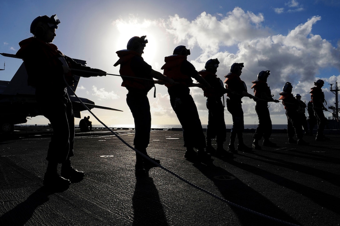 U.S. sailors hold the phone and distance line on the flight deck of the aircraft carrier USS Theodore Roosevelt next to the Military Sealift Command dry cargo and ammunition ship USNS Matthew Perry during a replenishment at sea in the Pacific Ocean, Nov. 9, 2015. The Roosevelt is operating in the U.S. 7th Fleet area of operations as part of a worldwide deployment. U.S. Navy photo by Petty Officer 3rd Class Anthony N. Hilkowski 
