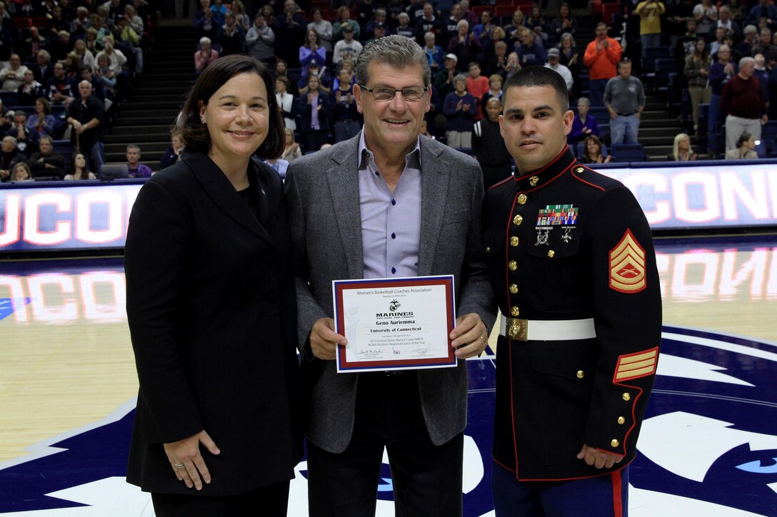 (Center) Geno Auriemma, the University of Connecticut’s Woman’s Basketball Coach, is awarded the 2015 United States Marine Corps/WBCA NCAA Division I Regional Coach of the Year, at the Harry A. Gampel Pavilion, Nov. 8. Gunnery Sgt. Manuel Beltran, right, and Danielle M. Donehew, left, the executive director for WBCA, presented Auriemma the award. The award is meant to recognize a coach for exemplary accomplishments throughout the year. (Official Marine Corps Photo by Staff Sgt. Richard Blumenstein) 