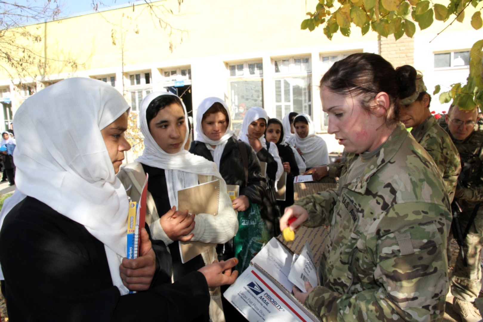 Army Sgt. Heather Carrier, a Kentucky Guard member with Agribusiness Development Team 3, passes out school supplies to Afghan students at a local school in Kapisa Province, Afghanistan Dec. 3, 2011.