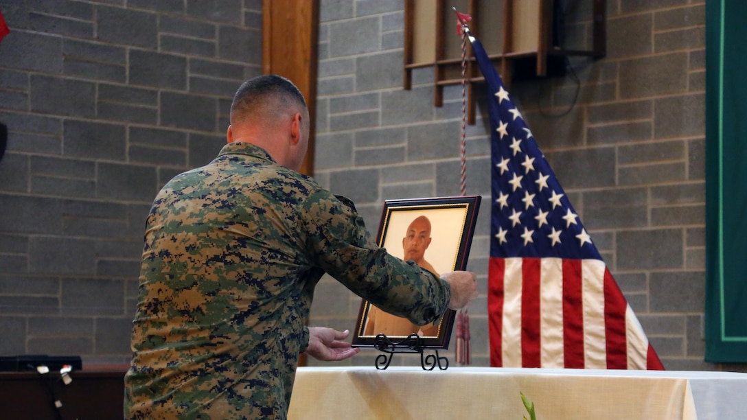 A Marine places a portrait of Staff Sgt. Denver Sugano on an altar during a memorial service at Marine Corps Air Station New River, N.C., Nov. 4, 2015.  Sugano faithfully served in the Marine Corps for 13 years, primarily serving as a flight equipment technician and a Marine recruiter. Sugano participated in three Unit Deployment Programs, assisted with Hurricane Sandy relief efforts and deployed in support of the 26th Marine Expeditionary Unit. Family, friends and fellow Marines remember Sugano for his dedication to his beloved Corps and his family.
