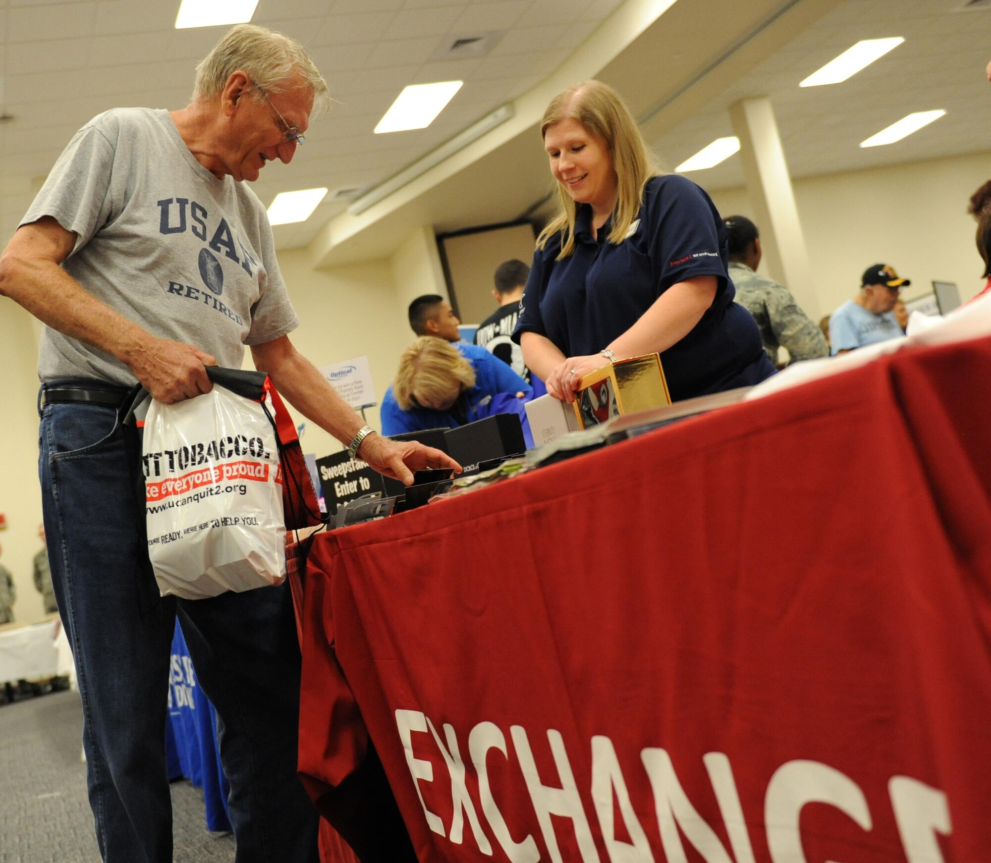 Retired Tech. Sgt. Frank Hacker inspects give-away items with the assistance of Jessica Foster, base exchange sales and merchandise manager, during Retiree Appreciation Day at the Roberts Consolidated Aircraft Maintenance Facility Nov. 6, 2015, Keesler Air Force Base, Miss.  The annual event sponsored by the Keesler Retiree office included more than 20 displays with information pertinent to retirees and a free lunch.  (U.S. Air Force photo by Kemberly Groue)