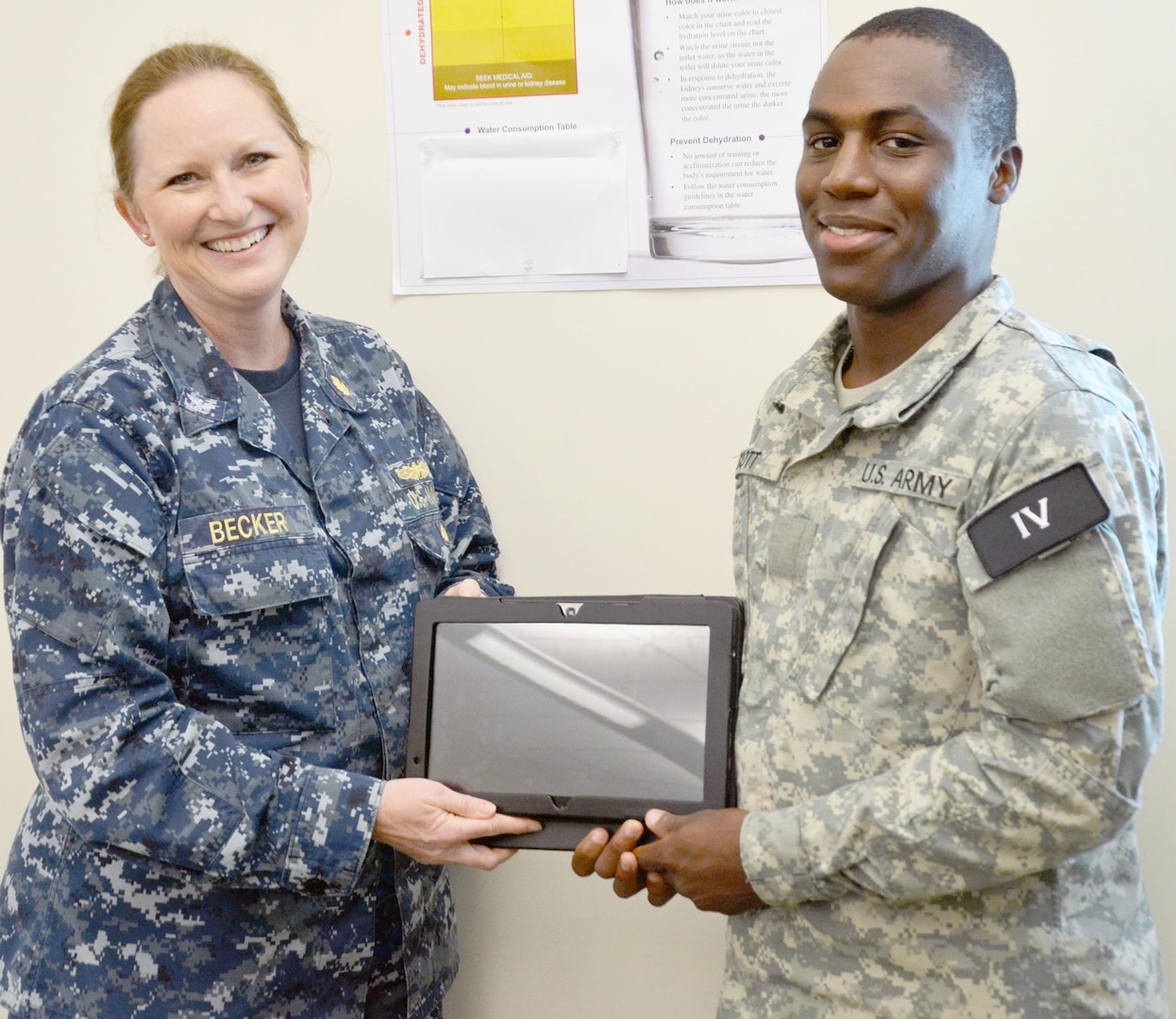 Navy Capt. Kathy Becker, Medical Education and Training Campus deputy commandant, presents a Slate tablet to Pvt. Darrion Scott, a student in the Public Health Specialist program, class 005-16. Scott’s class was one of two classes that was issued wireless laptops or Slates that are downloaded with course material as part of eMETC, a test pilot program to test the feasibility of using mobile devices to enhance learning ability. Students can use the devices to follow along with their instructors, take tests and study the material in their private time.