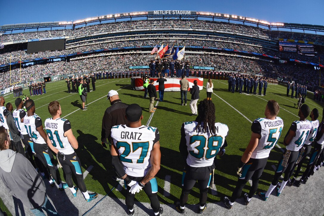 Jacksonville Jaguars football players observe service members from all U.S. military branches sing the national anthem at MetLife Stadium in East Rutherford, N.J., Nov 8, 2015, during a Veterans Day military appreciation football game where the New York Jets hosted the Jaguars. U.S. Navy photo by Petty Officer 1st Class Carlos M. Vazquez II