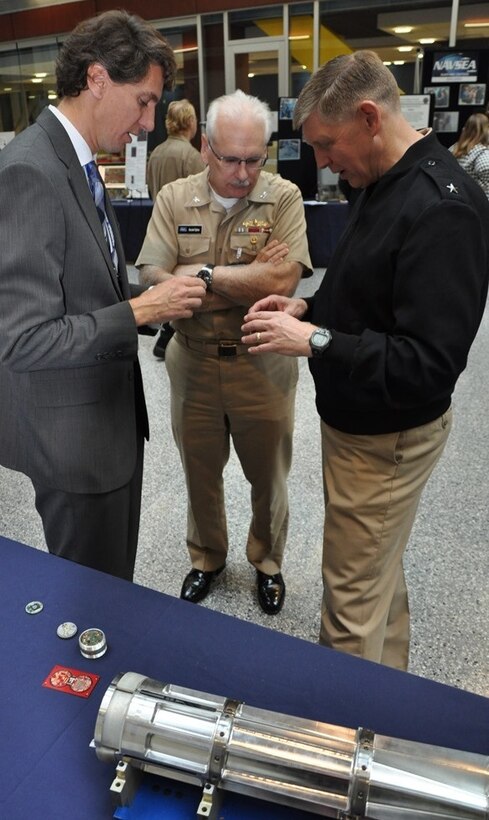 Hamish Malin, NSWCDD electromagnetic railgun projectile designer, briefs NSWC Commander Lorin Selby (right) and Navy Warfare Centers Chief of Staff Capt. Randell Dykes about the challenge of gun-hardening delicate electronics in his efforts to turn projectiles into guided missiles. 