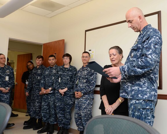 Sailors and civilian personnel look on as Cmdr. Raymond Bristol, officer-in-charge, Naval Branch Health Clinic Albany, presents Fran Quinn,  health benefits advisor, NBHC Albany, with commendations honoring her for 55 years of federal service in a retirement ceremony at Marine Corps Logistics Base Albany, Nov. 4. Quinn has spent the last 48 years of her extensive civil service career at NBHC Albany.
