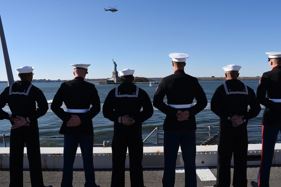 Sailors and Marines stand at parade rest while manning the rails as the amphibious landing dock ship USS New York pulls into port in New York City, Nov. 8, 2015. The dock ship is participating in Veterans Day activities throughout the week to honor the service of all veterans. U.S. Navy Photo by Petty Officer 3rd Class Andrew J. Sneeringer