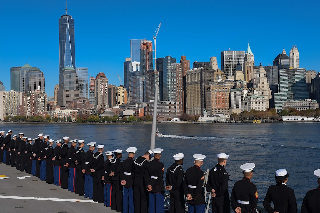 Sailors and Marines stand at parade rest while manning the rails as the amphibious landing dock ship USS New York pulls into port in New York City, Nov. 8, 2015. U.S. Navy Photo by Petty Officer 3rd Class Andrew J. Sneeringer