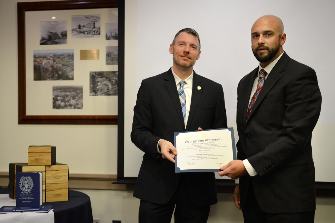 Walter Rankin, Deputy Dean of the Georgetown Univerity School of Continuing Studies presents Army veteran Josh Tredinnick a Certificate of Completion from Georgetown University, Washington, D.C., Oct. 22, 2015. The Dog Tag Bakery is operated by the administration and faculty of Georgetown University’s School of Continuing Studies and helps rehabilitate disabled veterans by training them in the art of baking. DoD photo by Marvin Lynchard