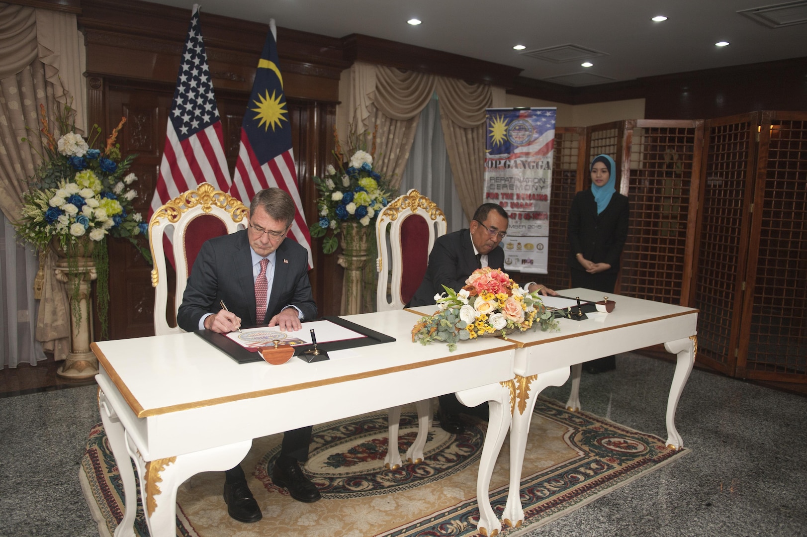 U.S. Secretary of Defense Ashton Carter and Malaysia Deputy Defense Minister Dato’ Wira Mohd Johari Bin Baharum officially sign documents turning over remains of a U.S. service member prior to a repatriation ceremony at Subang Air Base, Malaysia, Nov. 5, 2015. The joint effort between the U.S. and Malaysia culminated in a 25-day mission from Aug. 16 through Sept. 9, 2015, at a crash site near Beruas village, Manjung district, Perak state, Malaysia. The mission resulted in the success of finding osseous remains as well as material evidence. The partnership between the two countries marks the first of its kind. The mission of the Defense POW/MIA Accounting Agency is to provide the fullest possible accounting for our missing personnel to their families and the nation. (U.S. Air Force photo by Staff Sgt. Brian J. Valencia)