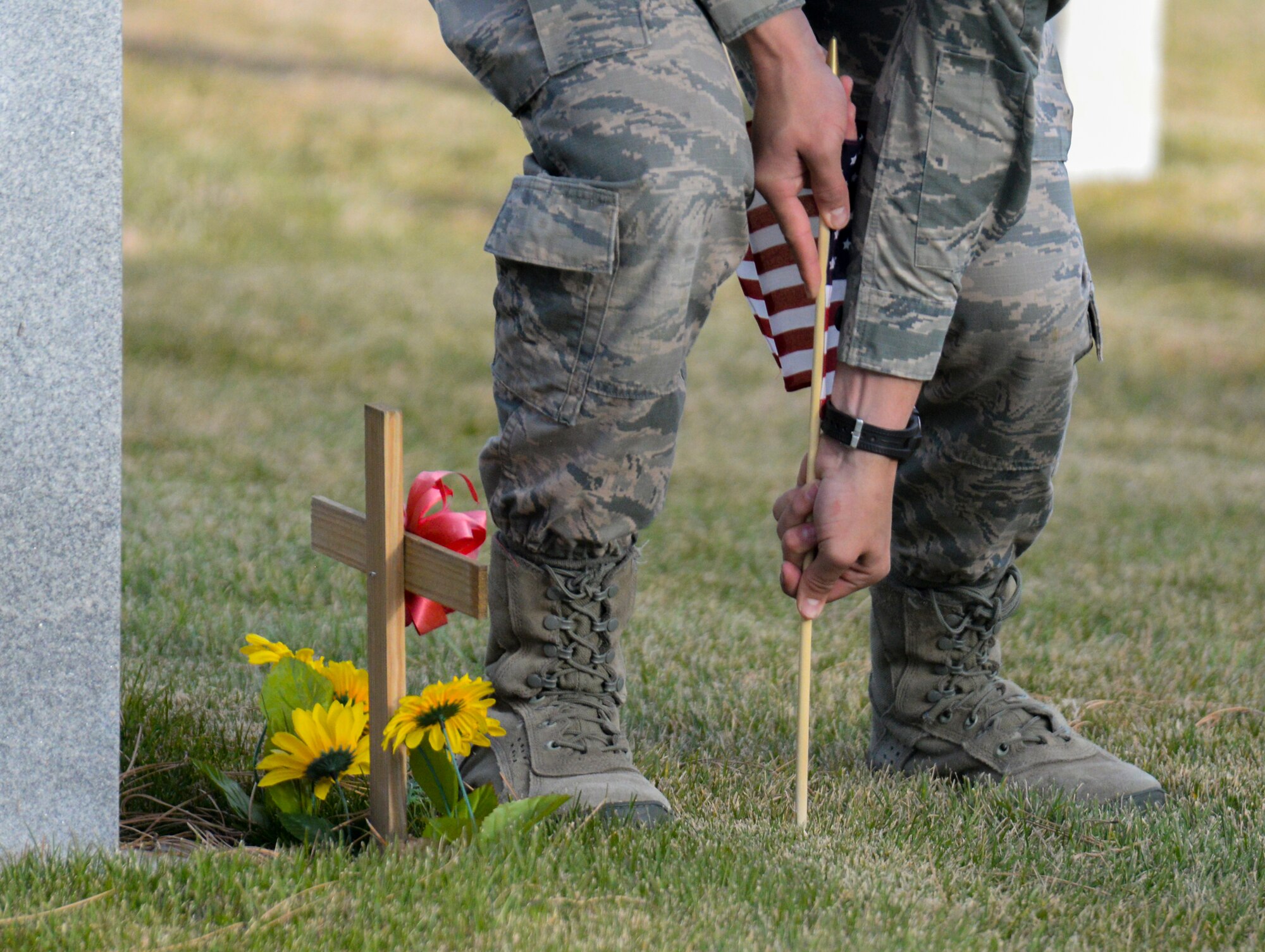 Airman 1st Class Michael Dawkins, 90th Missile Wing ceremonial guardsman from the 90th Security Forces Squadron, places an American flag in the ground in from of the headstone of a veteran in the F.E. Warren Air Force Base, Wyo., cemetery Nov. 9, 2015. For Veterans Day, Airmen from the 90th Missile Wing Honor Guard and 90th FSS placed flags at each veteran's grave and rendered a salute in honor of their service. (U.S. Air Force photo by Senior Airman Jason Wiese)
