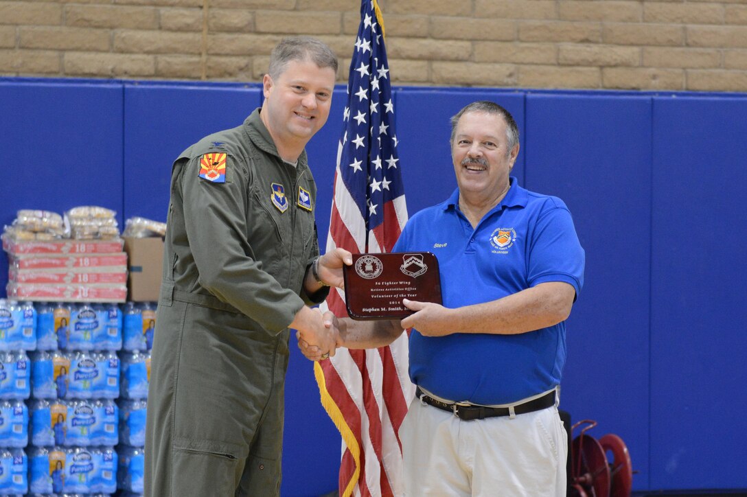Col. David Shoemaker, 56th Fighter Wing vice commander, hands the retiree activities office volunteer of the year plaque to Stephen Smith, Retired Activities Office civilian, during Retiree Appreciation Day at Luke Air Force Base, Arizona, Nov. 7, 2015. (U.S. Air Force photo by Senior Airman James Hensley)