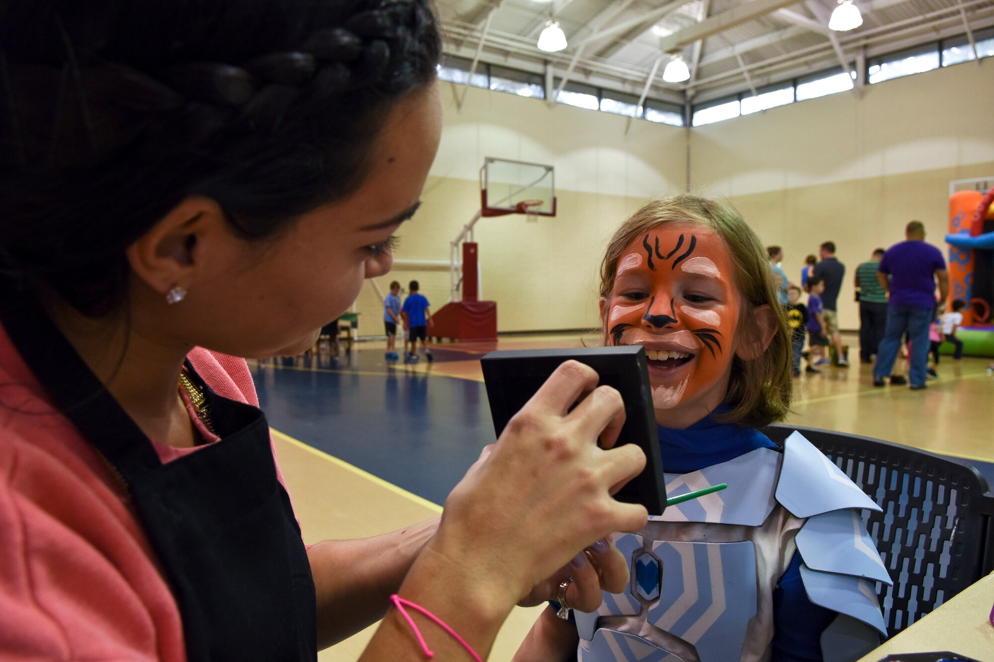 Erica Dechane (left), wife of Senior Airman Paul Dechane, 911th Air Refueling Squadron crew chief, holds a mirror after painting the face of the child of Staff Sgt. Michael Bradshaw, 4th Aircraft Maintenance Squadron weapons load crew team member, during the Military Family Appreciation Month celebration, Nov. 7, 2015, at Seymour Johnson Air Force Base, North Carolina. The event featured multiple activities, including face painting, a bouncy house and an arts and crafts table. In 1993, November was declared Military Family Appreciation Month by the Armed Services YMCA. (U.S. Air Force photo/Senior Airman Aaron J. Jenne)