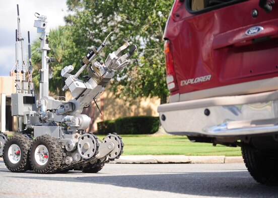 An explosive ordnance disposal robot approaches a simulated car crash Nov. 6 at the Airey Avenue intersection to inspect a simulated suspicious package. This training exercise was in support of the Crown Royal 16-1 exercise. (U.S. Air Force photo by Senior Airman Solomon Cook/Released)

