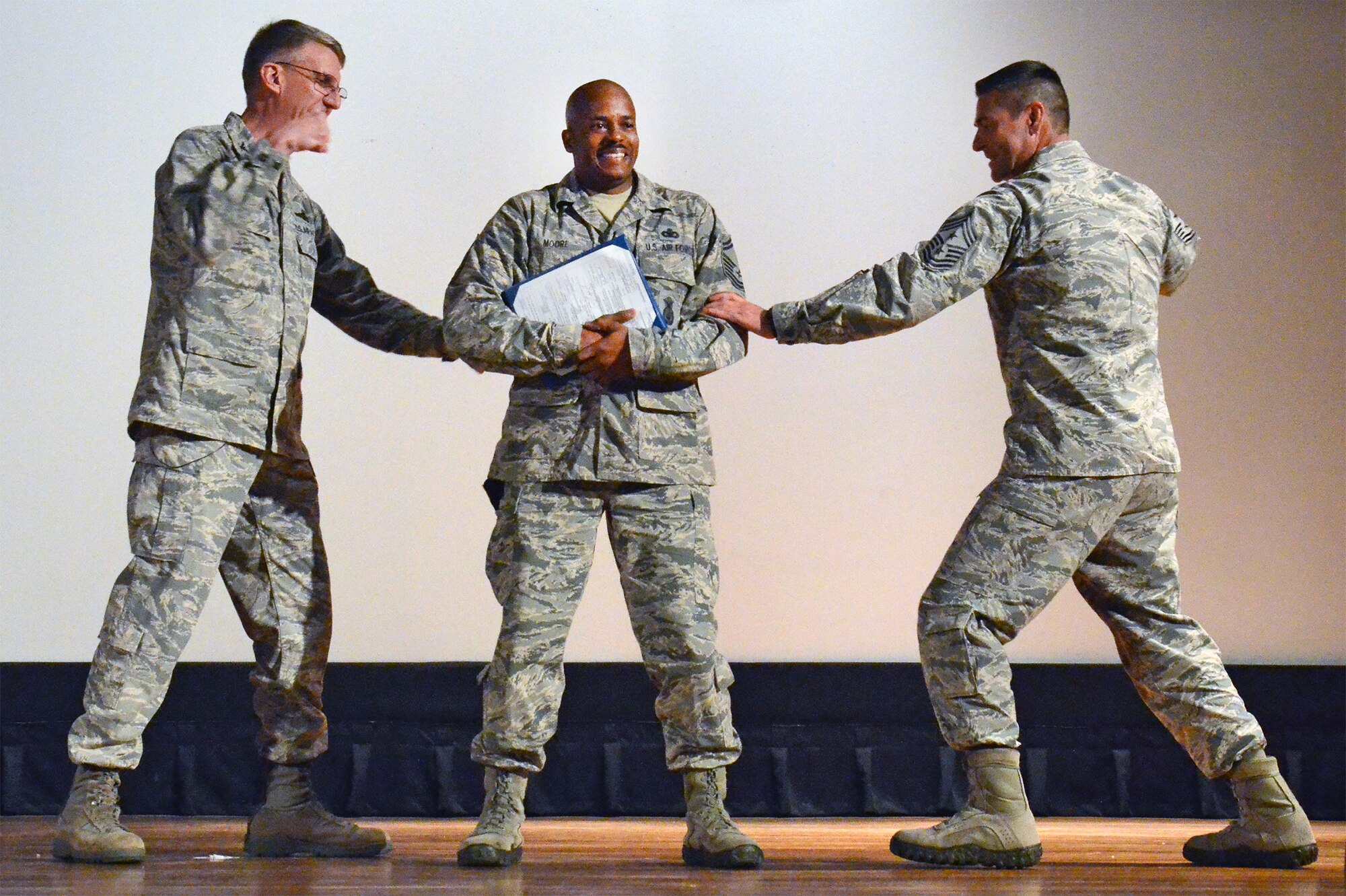 Senior Master Sgt. Stacie Moore, a reservist with the 920th Rescue Wing here, prepares for impact as part of his promotion to chief master sergeant during a commander’s call held at the base theater here Nov. 8. To Sergeant Moore’s right is wing commander Col. Jeffrey Macrander, with wing command chief, Chief Master Sgt. Timothy Bianchi to Sergeant Moore’s left. (U.S. Air Force photo/Master Sgt. Paul Flipse) 