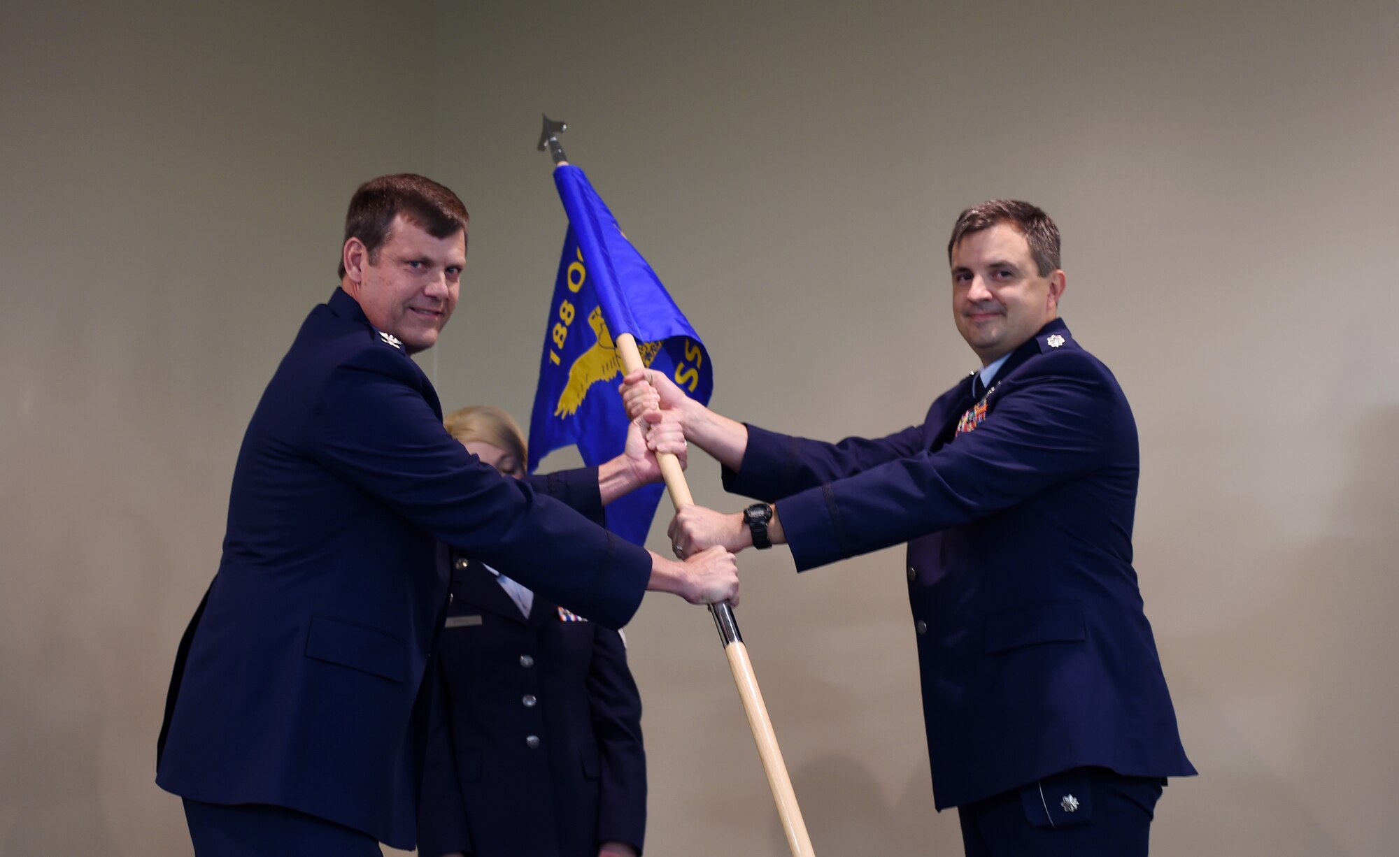 Lt. Col. Patric Coggin (right) receives the 188th Operations Support Squadron guidon from Col. Brian Burger, 188th Operations Group commander, during a formal assumption of command held at Ebbing Air National Guard Base, Fort Smith, Ark. Nov. 7, 2015. Coggin will oversee the 188th OSS, which is responsible for providing support to the MQ-9 Reaper operation for the 188th OG. The 188th OSS requires the expertise of intelligence, operations, communications and weather specialists. (U.S. Air National Guard photo by Staff Sgt. Hannah Dickerson/Released)