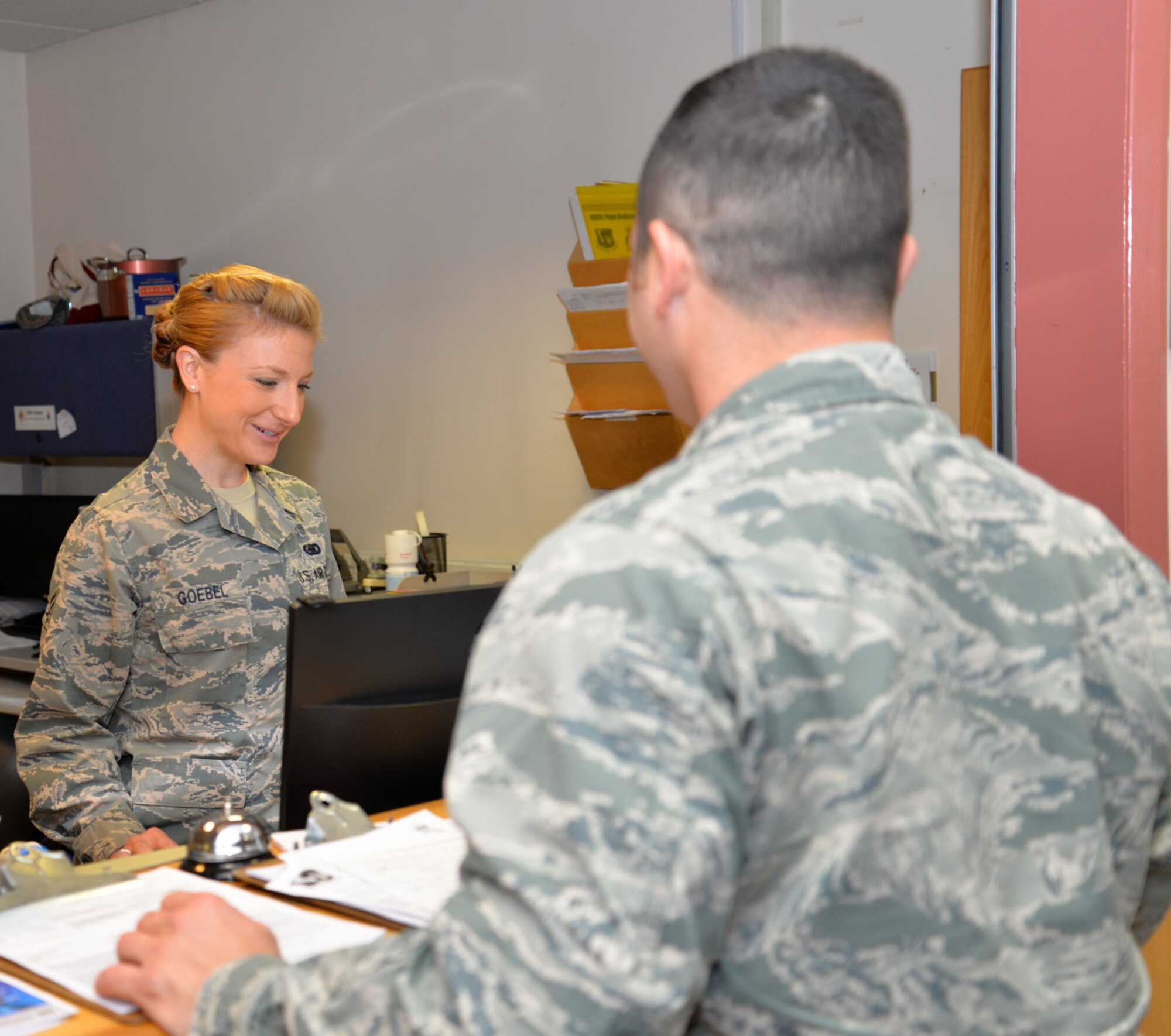 U.S. Air Force Senior Airman Elizabeth Goebel, left, 48th Aerospace Medicine Squadron Flight Medicine Clinic flight and operational medical technician, chats with a patient as she checks his medical records Oct. 21, 2015, on RAF Mildenhall, England. Although assigned to RAF Lakenheath, Goebel is one of several medical technicians working at the clinic on RAF Mildenhall supporting Team Mildenhall’s aircrew and dependents, as well as U.S. Air Force firefighters. (U.S. Air Force photo by Karen Abeyasekere/Released)