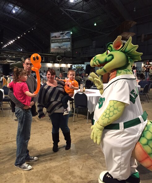 Senior Airman Jesse Mitchell of the 18th Intelligence Squadron, and his wife Kayla, son Noah and daughter Sophia, talk with the Dayton Dragons mascot Heater during the event. Mitchell deployed in January 2015 and welcomed back home with his family in July 2015. (Skywrighter photo/Amy Rollins)