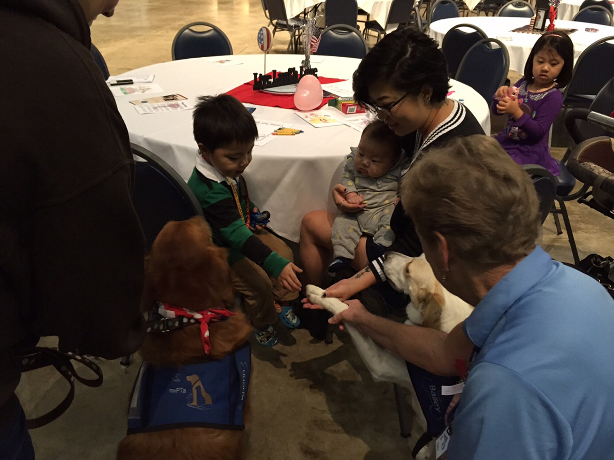 Marine Capt. Anthony Suh, an environmental engineering student at the Air Force Institute of Technology, brought his wife Sylvia, daughter Evelyn and sons, Elijah and Emmett to the event where they enjoyed the attention of dogs, Renn and Bailey, from the Miami Valley Pet Therapy Association. (Skywrighter photo/Amy Rollins)