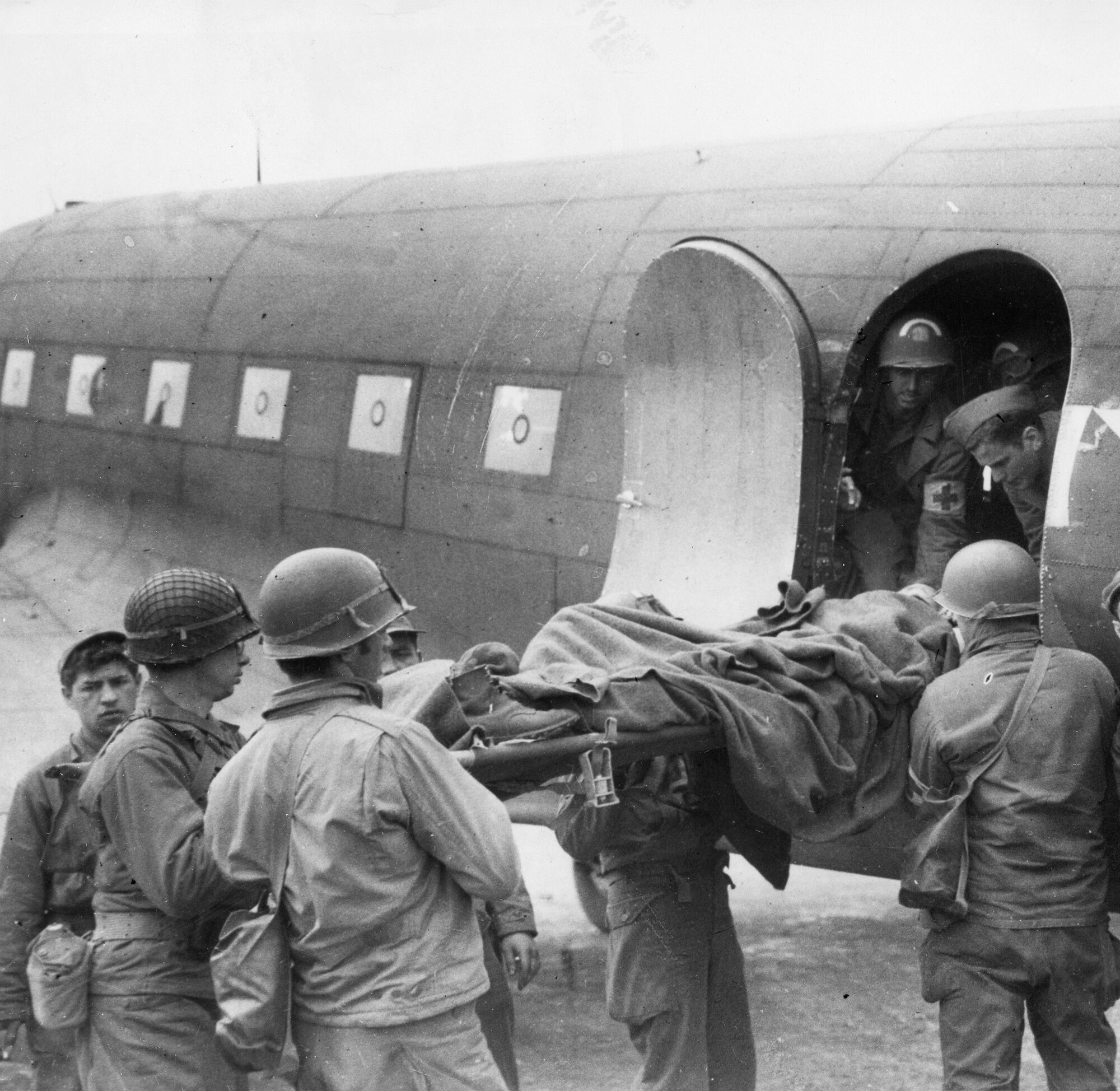Soldiers and medics load a wounded comrade onto a C-47 Skytrain for transport from France to England during the Brittany Campaign. (Photo Credit: AFMS Historian’s Office)
