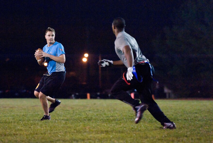 Andrew Muench, 9th Airlift Squadron quarterback, drops back and looks downfield for an open receiver as Irvin Ward, 436th Logistics Readiness Squadron lineman, chases him Nov. 4, 2015, on Dover Air Force Base, Del. Losing 27-7, the 9th AS could not get into an offensive rhythm against the 436th LRS in a Dover AFB intramural flag football game for the top spot in the American Football Conference. (U.S. Air Force photo/Roland Balik)