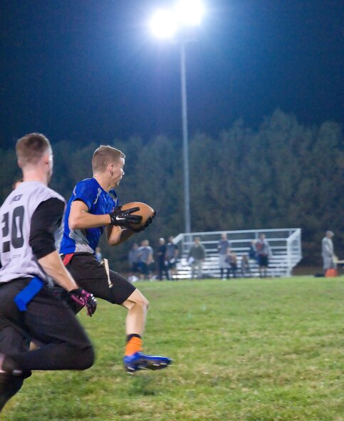 Guy Crawford, 9th Airlift Squadron receiver, runs away from the grasp of Joshua Orick, 436th Logistics Readiness Squadron defender, Nov. 4, 2015, on Dover Air Force Base, Del. Crawford had a strong game against LRS but his efforts were not enough to keep pace with the 436th LRS team in a Dover AFB intramural flag football American Football Conference game, losing 27-7 to LRS and dropping down to second place in the standings. (U.S. Air Force photo/Roland Balik)