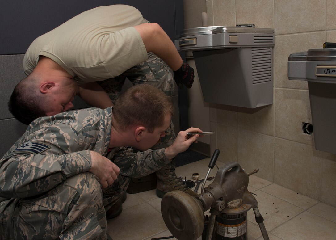 U.S. Air Force Staff Sgt. Ronald Owen and Senior Airman Randall Schultz, 633rd Civil Engineer Squadron water and fuel systems maintenance technicians, look into a drain line before clearing it at Langley Air Force Base, Va., Nov. 6, 2015. Owen and Schultz utilized a K-50 drain cleaning snake to clear the drain line of any possible or unseen blockage. (U.S. Air Force photo by Staff Sgt. John D. Strong II/Released)