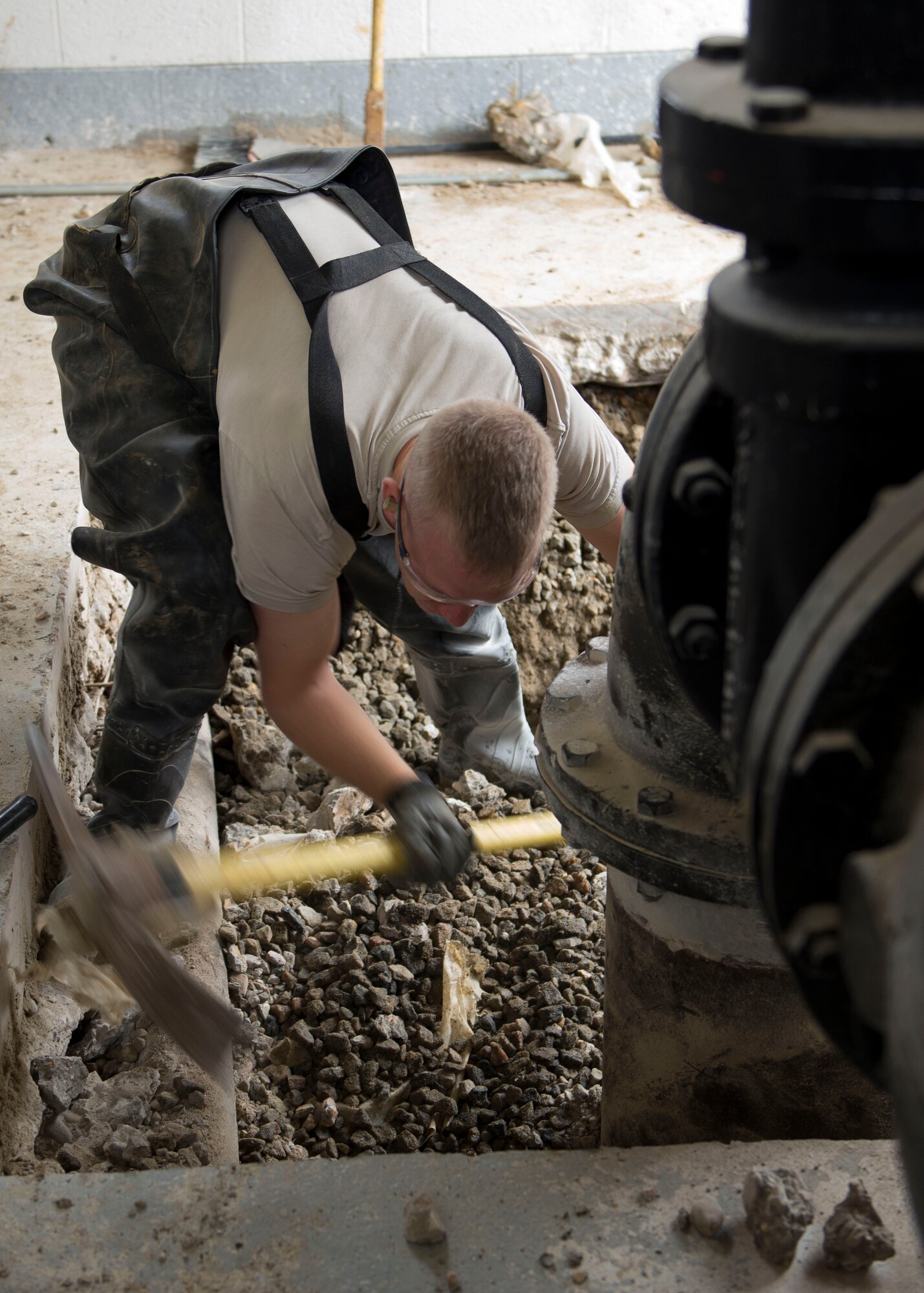 U.S. Air Force Senior Airman Walter Smith, 633rd Civil Engineer Squadron water and fuel systems maintenance technician, uses a pick to expose a damaged pipe at Langley Air Force Base, Va., Nov. 6, 2015. The CES team repaired the damage that was a result of two failed pipe restraint systems beneath concrete floors. (U.S. Air Force photo by Staff Sgt. John D. Strong II/Released)