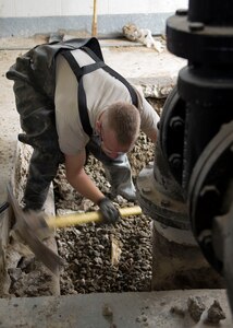 U.S. Air Force Senior Airman Walter Smith, 633rd Civil Engineer Squadron water and fuel systems maintenance technician, uses a pick to expose a damaged pipe at Langley Air Force Base, Va., Nov. 6, 2015. The CES team repaired the damage that was a result of two failed pipe restraint systems beneath concrete floors. (U.S. Air Force photo by Staff Sgt. John D. Strong II/Released)
