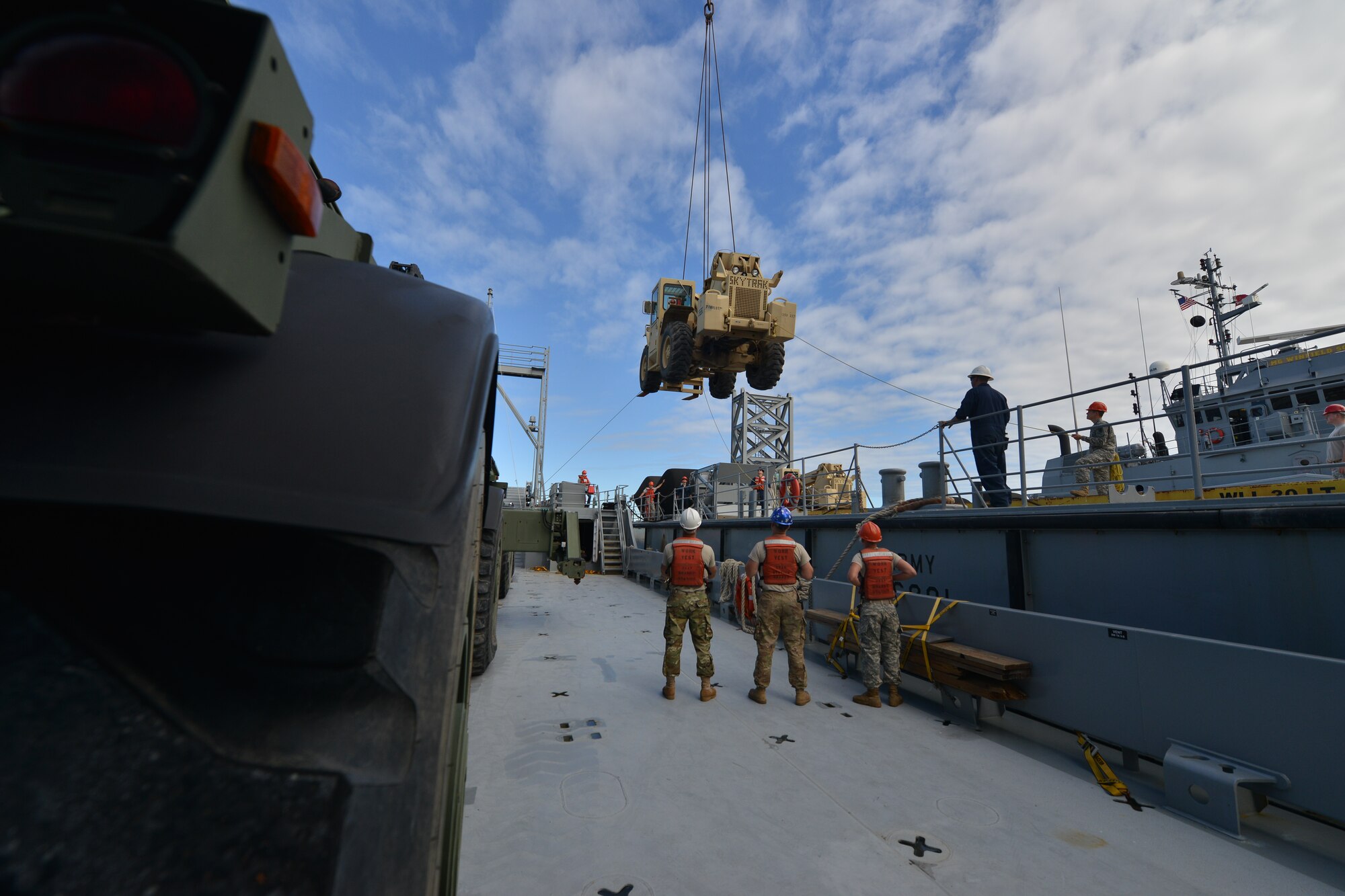 Crew members of the U.S. Army Vessel Brandy Station assigned to 97th Transportation Company observe as the 73rd Trans. Co. operates a crane to move a fork lift onto the Brandy Station on the James River in Newport News, Va., Nov. 3, 2015. As the vehicle landed on the vessel, the Brandy Station crew guided it into place and secured it to the platform. (U.S. Air Force photo by Staff Sgt. Natasha Stannard/Released)