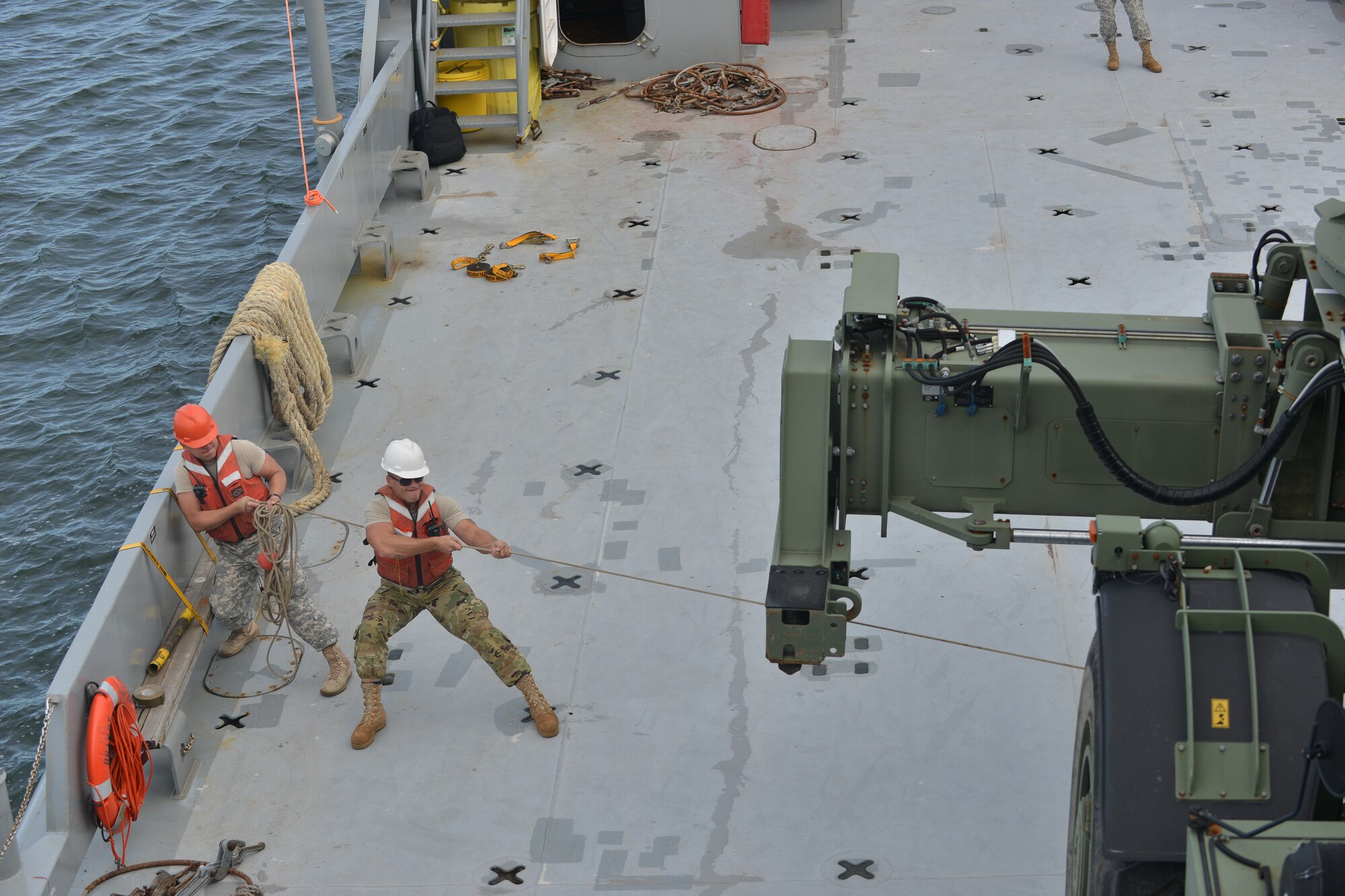 Crew members of the U.S. Army Vessel Brandy Station assigned to 97th Transportation Company guide a more than 50,000 pound Kalmar rough terrain container handler onto a vessel on the James River in Newport News, Va., Nov. 3, 2015. This was the first time the newly formed crew members moved heavy equipment from a barge crane to their vessel as a team. (U.S. Air Force photo by Staff Sgt. Natasha Stannard/Released)