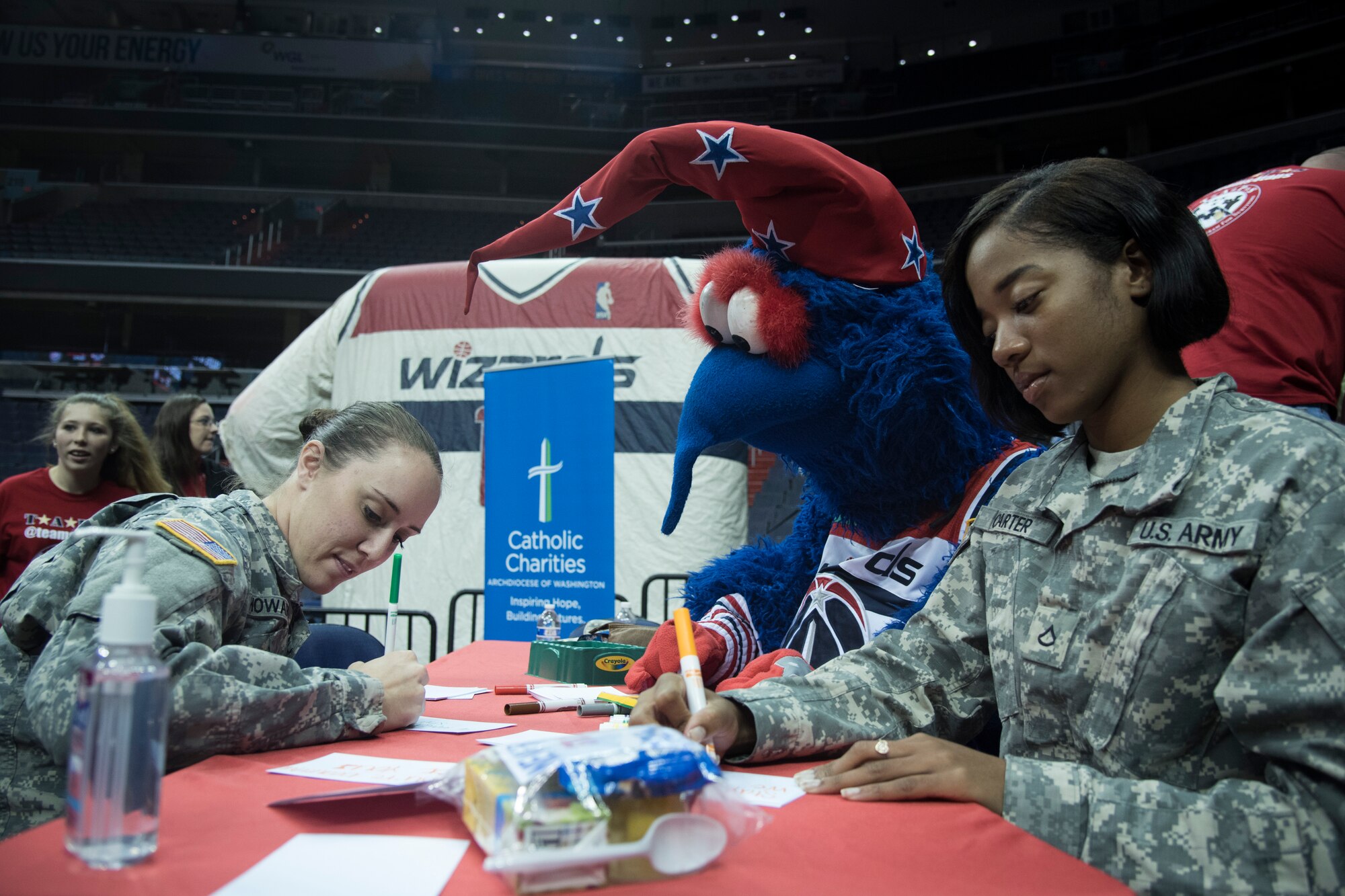 Military members and G-Wiz, Washington Wizards mascot, write notes of encouragement to put inside bags of food for homeless military veterans during a Salute to the Stars event at the Verizon Center in Washington, D.C., Nov. 9, 2015. Salute to the Stars, an annual event held by the Wizards, had military members team up with the local National Basketball Association team to bag food for homeless military veterans that included juice boxes, fruit cups, raisins and various other foods. (U.S. Air Force photo by Airman 1st Class Philip Bryant/Released)