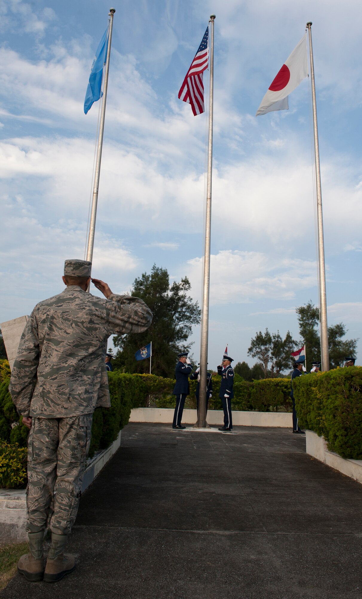 U.S. Air Force Maj. Yogi Lebby, 18th Component Maintenance Squadron commander, salutes the American, Japanese, and North Atlantic Treaty Organization flags during a Veterans Day ceremony Nov. 11, 2015, at Kadena Air Base, Japan. The flags symbolize the relationships between these entities and Veterans Day commemorates the sacrifices made by all service members. (U.S. Air Force photo by Airman 1st Class Lynette M. Rolen)