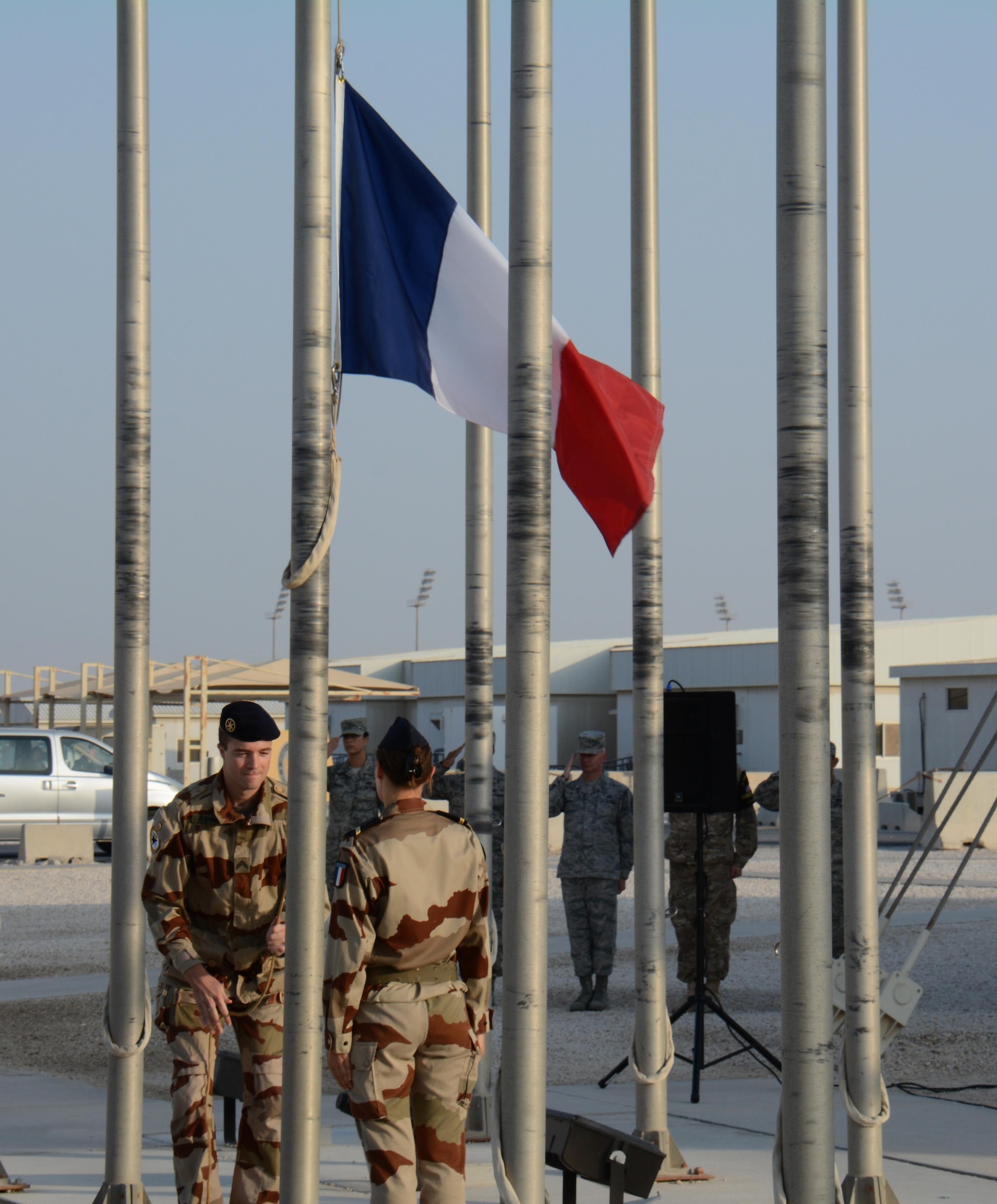 French service members raise the French flag during a flag raising ceremony to honor past service members Nov. 11 at Al Udeid Air Base, Qatar. French soldiers alongside service members from other nations gathered to commemorate the end of World War I, known in Europe as Armistice Day. (U.S. Air Force photo by Tech. Sgt. James Hodgman/Released)