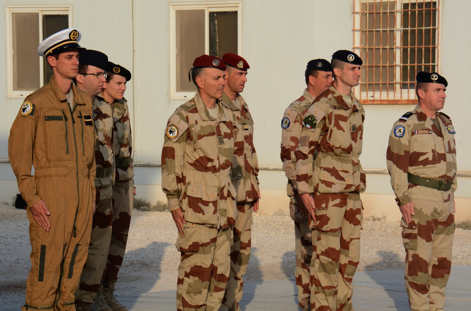 Service members stand in formation during a flag raising ceremony to honor past service members Nov. 11 as the French flag is raised at Al Udeid Air Base, Qatar. French soldiers alongside service members from other nations gathered to commemorate the end of World War I, known in Europe as Armistice Day. (U.S. Air Force photo by Tech. Sgt. James Hodgman/Released)