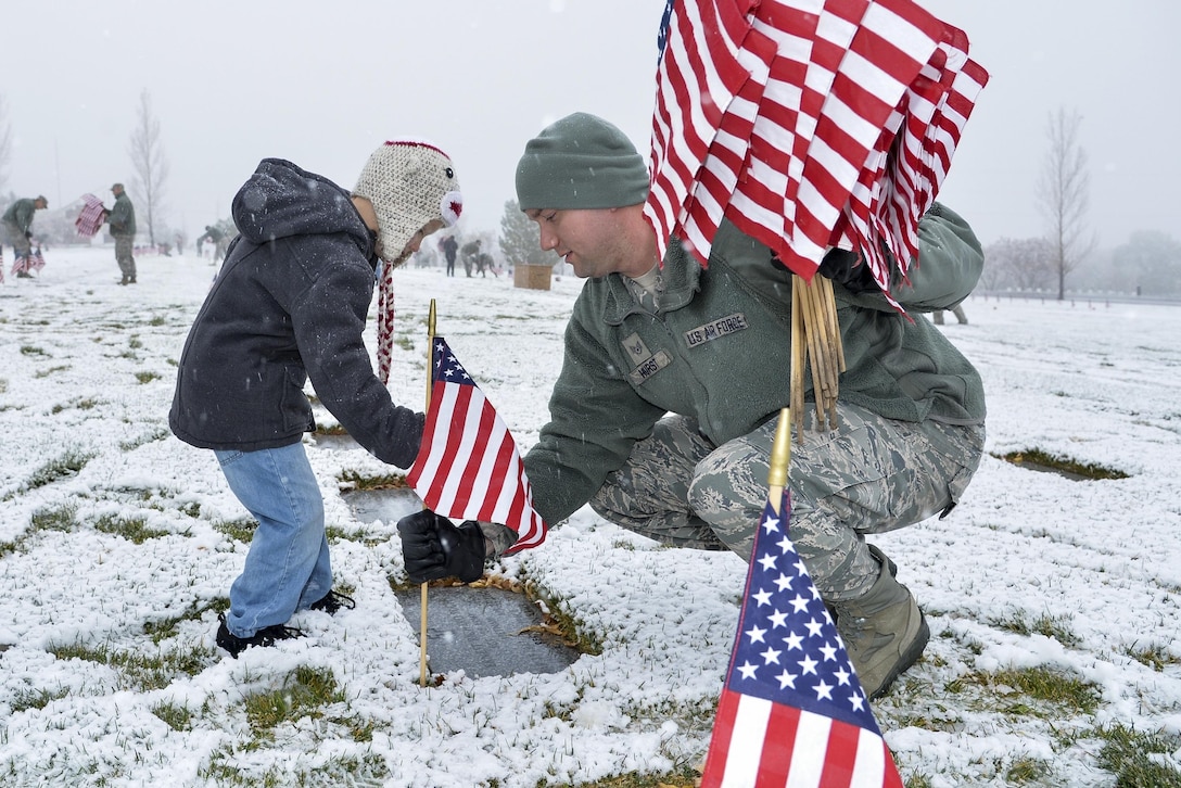 Air Force Staff Sgt. Louis Hurst and son, Ethan, place a flag beside a burial site at the Utah Veterans Memorial Cemetery in Bluffdale, Utah, Nov. 10, 2015. More than 100 airmen from Hill Air Force Base participated in the flag-placing detail organized by the Air Force Sergeants Association Chapter 1163. U.S. Air Force photo by R. Nial Bradshaw
