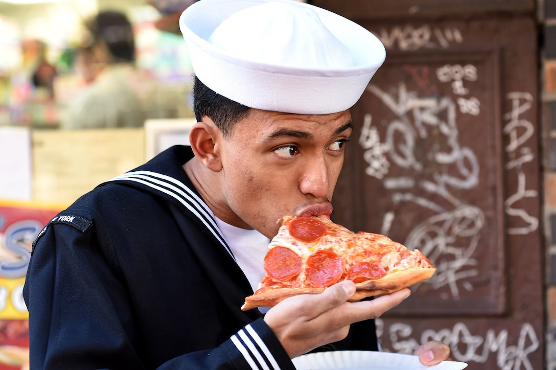 Navy Seaman Kevin Carranza enjoys a slice of pizza while participating in Veterans Day events in New York City, Nov. 9, 2015. Carranza is a hospitalman apprentice assigned to the USS New York. U.S. Navy photo by Petty Officer 1st Class Brian McNeal