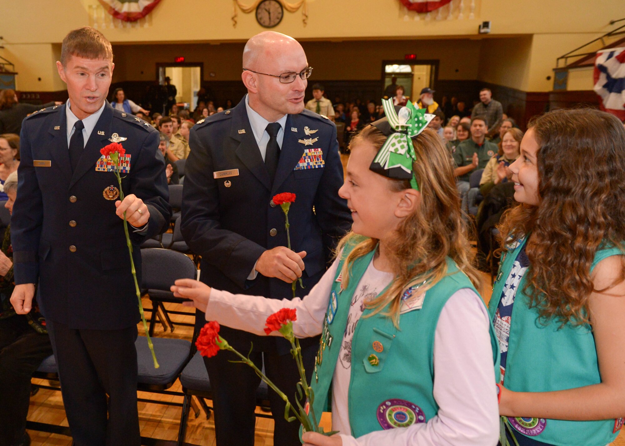 Maj. Gen. Craig Olson, left, C3I and Networks program executive officer, and Lt. Col David Dunklee, 66th Air Base Group deputy commander, accept flowers from local Girl Scouts at the town of Lexington's annual Veterans Day ceremony Nov. 11. Several local towns surrounding Hanscom honored military service members during Veterans Day observances. (U.S. Air Force photo by Jerry Saslav) 