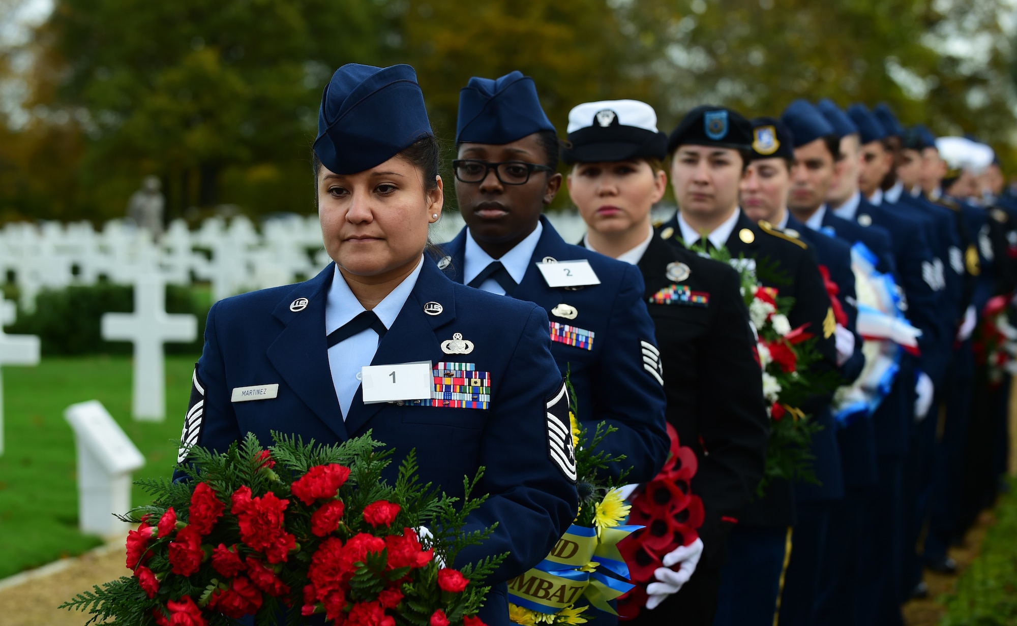 U.S. Air Force Master Sgt. Jackie Martinez, 501st Combat Support Wing logistics superintendent, and other Service members from the 501st CSW and tenant units at RAF Molesworth, carry wreaths during the Veterans Day ceremony at Cambridge American Cemetery, United Kingdom, Nov. 11, 2015. The wreaths were laid in honor the military members past and present. (U.S. Air Force photo by Master Sgt. Chrissy Best/Released)
