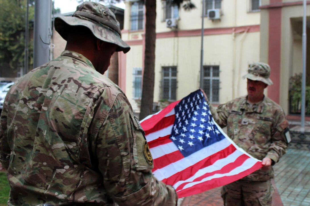 U.S. Navy Lt. Cmdr. Al Dozier, left, assists U.S. Navy Capt. Mark Edwards raise the U.S. flag while participating in a Veterans Day ceremony on Resolute Support Headquarters, Kabul, Afghanistan, Nov. 11, 2015. U.S. Navy photo by Lt. Charity Edgar
