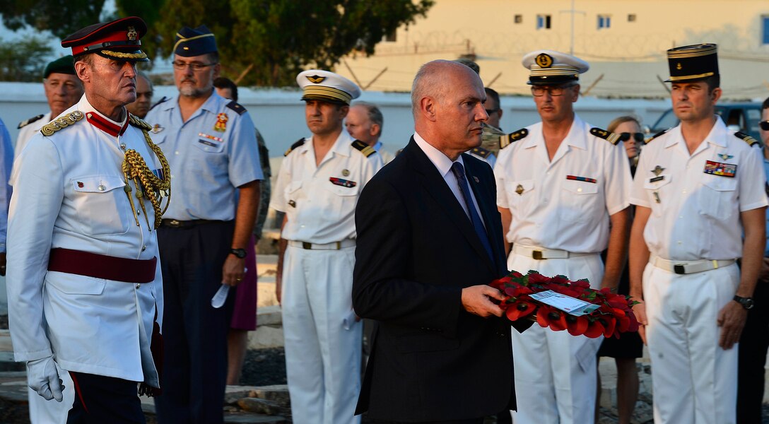 Greg Dorey, British ambassador to Ethiopia and Djibouti, and British Army Col. Mike Scott, defense attaché, prepare to lay a wreath of poppies during Remembrance Day service near Camp Lemonnier, Djibouti, Nov. 11, 2015. The red poppy became an emblem of Remembrance Day and a tradition for countries across the world to honor military veterans. U.S. Air Force photo by Tech. Sgt. Dan DeCook