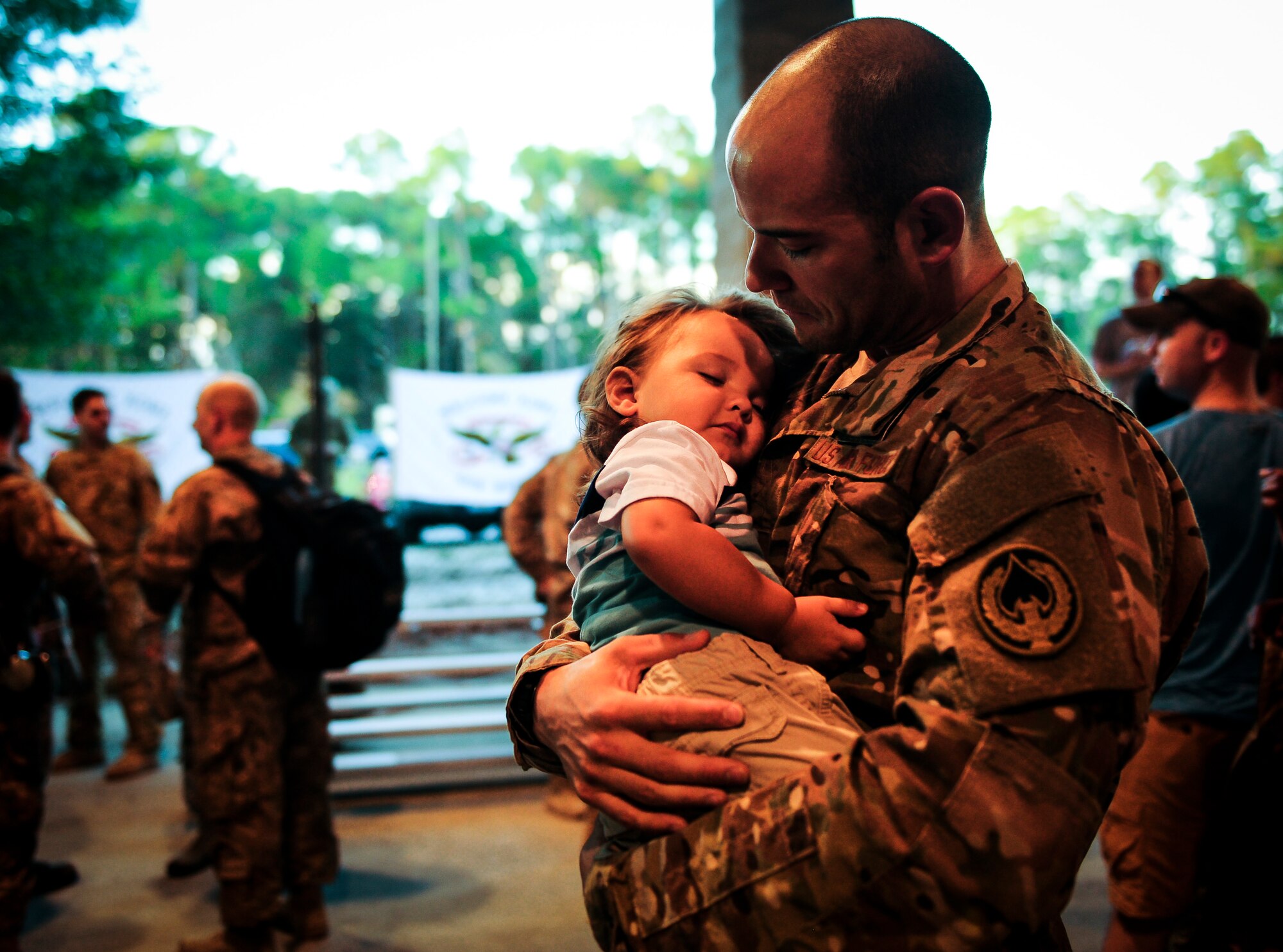Tech Sgt. Corey Poley, a communications navigator craftsman with the 4th Special Operations Squadron, holds his sleeping son during Operation Homecoming at Hurlburt Field, Fla., Nov. 6, 2015. Operation Homecoming is a program created to welcome home Airmen returning from a recent deployment. (U.S. Air Force photo by Senior Airman Meagan Schutter)