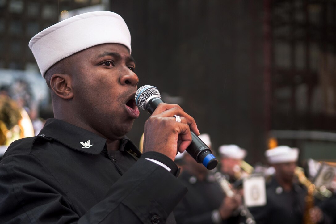 Navy Petty Officer 3rd Class Julius Coker sings with the U.S. Fleet Forces Band at the Band of Pride Concert in Times Square during a Veterans Day event in New York City, Nov. 10, 2015. Coker is a musician. U.S. Navy photo by Petty Officer 2nd Class Nancy C. diBenedetto