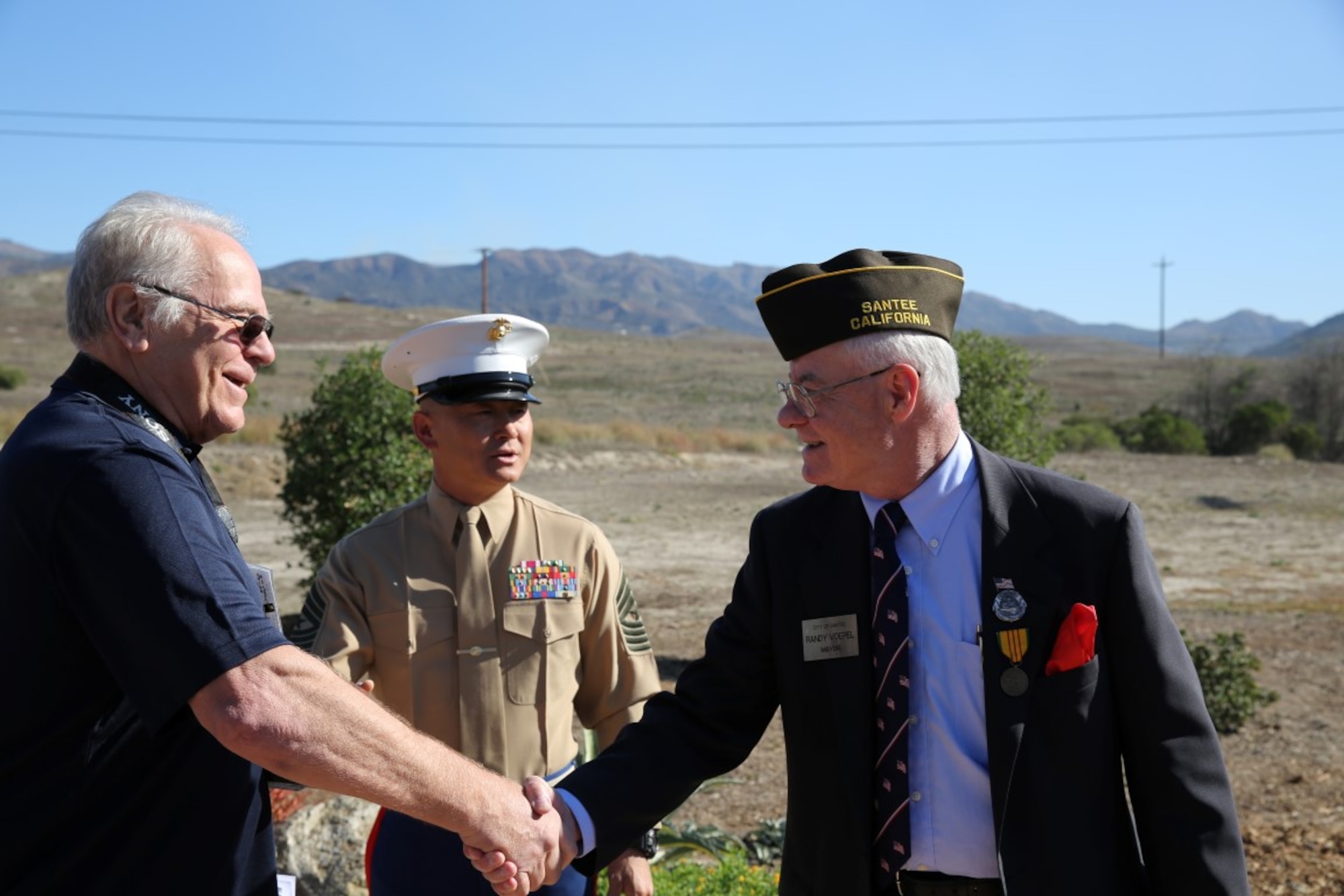 Randy Voepel, right, mayor of Santee, Calif., and Vietnam veteran, welcomes guests alongside U.S. Marine Sgt. Maj. Jason Boldenow, center, battalion sergeant major for 2nd Battalion, 1st Marine Regiment, the ground combat element of the 13th Marine Expeditionary Unit, prior to a Nov. 6 ceremony honoring members of their regiment who gave their lives during the Vietnam War. During the ceremony, plaques bearing the names of the fallen were dedicated in their honor at the Camp Horno Memorial Garden aboard Camp Pendleton, Calif. (U.S. Marine Corps photo by Sgt. Paris Capers/ Released)