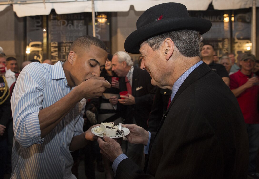 Terry Ebbert (right), a retired Marine colonel, passes cake to Lance Cpl. Devan A. Barnett (left) during a cake cutting ceremony at Luke restaurant in New Orleans, Nov. 10, 2015. Ebbert and Barnett were the oldest and youngest Marine, respectively, present during the ceremony. The passing of the cake from the oldest Marine to the youngest Marine symbolizes the passing of knowledge and traditions from one generation to the next. (U.S. Marine Corps photo by Cpl. Ian Leones/Released)