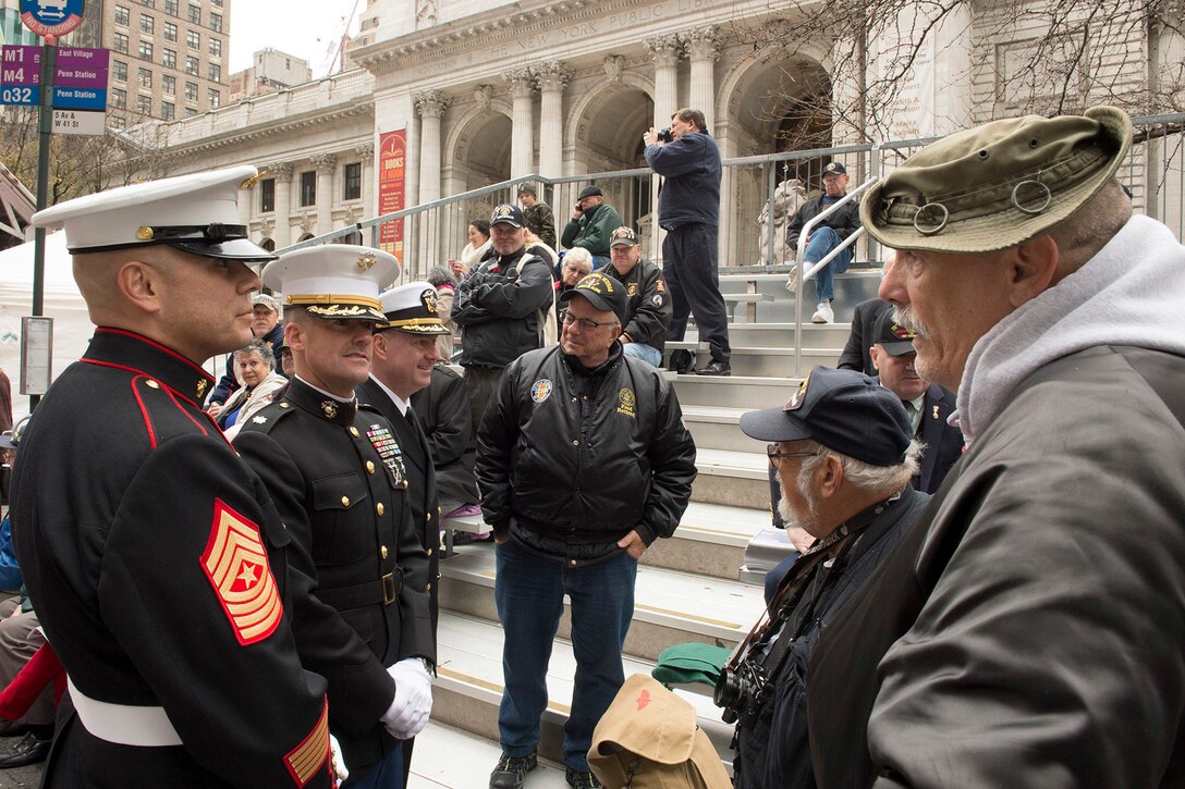 Marine Corps Sgt. Maj. Ramiro Olmos, left, Marine Corps Lt. Col. Shannon Shea, center left, and Navy Cmdr. Corey Barker share stories with veterans during the 2015 New York City Veterans Day Parade in New York, Nov. 11, 2015. U.S. Navy photo by Petty Officer 1st Class Brian McNeal