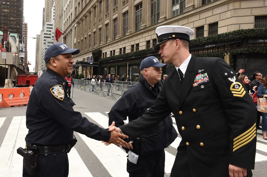 A Navy Master Chief Petty Officer assigned to the USS New York, greets a New York City policeman while marching in the 2015 New York City Veterans Day Parade in New York, Nov. 11, 2015. U.S. Navy photo by Petty Officer 1st Class Brian McNeal